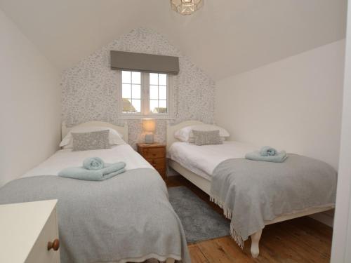 two twin beds in a bedroom with a window at 3 Bed in Burton Bradstock DC055 in Burton Bradstock