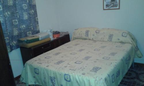 a small bedroom with a bed with a blanket on it at Sierras Chicas La Granja in Córdoba