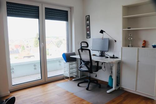 an office with a desk and a chair and windows at Komfortables Penthouse 200 qm in Langen