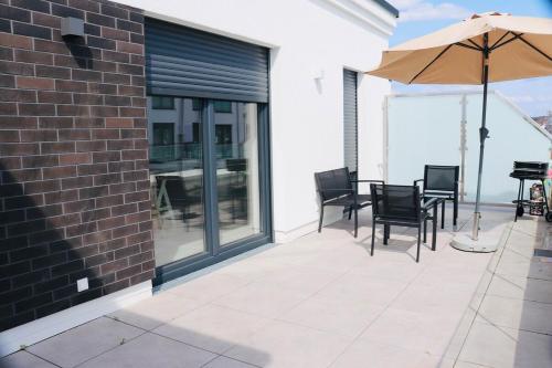 a patio with a table and chairs and an umbrella at Komfortables Penthouse 200 qm in Langen