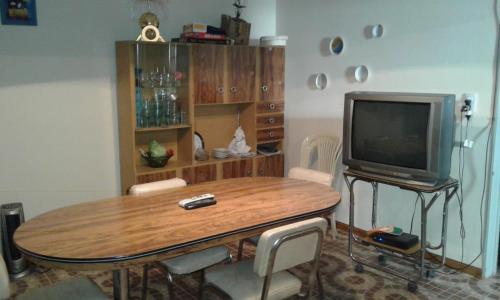 a living room with a wooden table and a television at Sierras Chicas La Granja in Córdoba