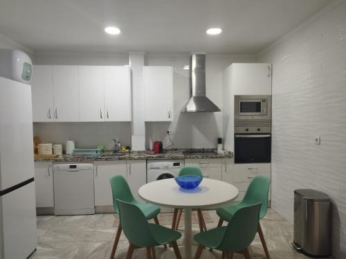 a kitchen with a table and green chairs at ★★APARTAMENTOS MARIN★★ in Alicante