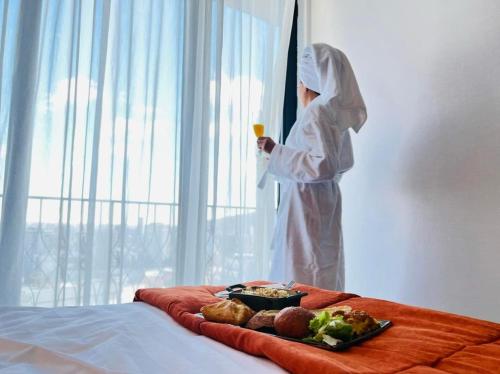 a person dressed in white holding a glass of juice and a tray of food at Biography Design Tbilisi in Tbilisi City