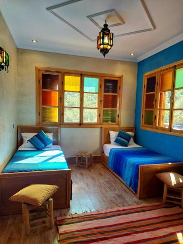 two beds in a room with blue walls and windows at DAR EL HACHIMI EL IDRISSI in Ourika