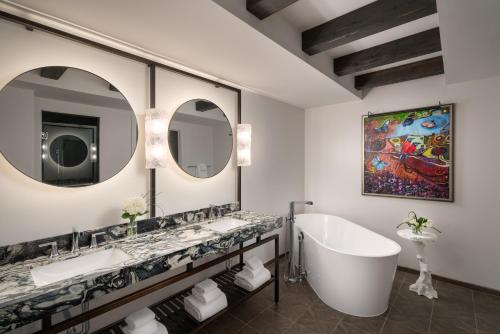 a bathroom with two sinks and a tub and mirrors at Grand Bohemian Lodge Greenville, Autograph Collection in Greenville
