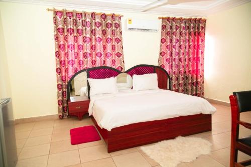 1 dormitorio con 1 cama grande y cortinas rojas en HILLS HAVEN HOTEL, en Accra