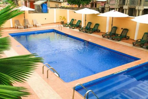 a large swimming pool with chairs and umbrellas at HILLS HAVEN HOTEL in Accra