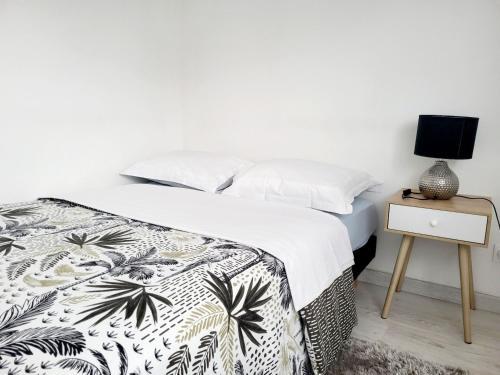 1 dormitorio con 1 cama y mesita de noche con lámpara en Studio cosy proche Paris Orly, en Morangis
