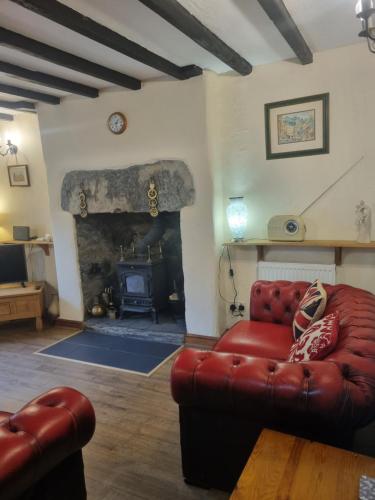 a living room with a red couch and a fireplace at Llugwy Cottage in Betws-y-coed
