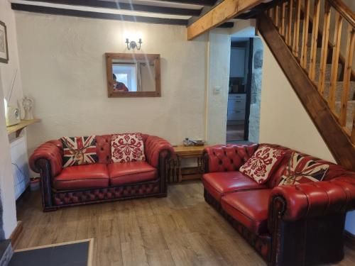 a living room with two red leather couches and a mirror at Llugwy Cottage in Betws-y-coed