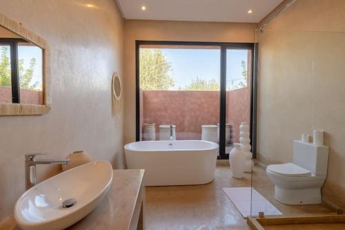 a bathroom with a tub and a toilet and a sink at Villa Dar Pampa Marrakech in Marrakesh