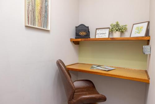 a desk with a chair and a clock on a wall at Hartwell Suites in Hartwell
