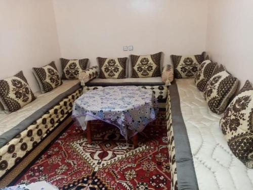 ein Wohnzimmer mit einem Sofa mit Kissen und einem Tisch in der Unterkunft Dar El Ghali in Er Rachidia