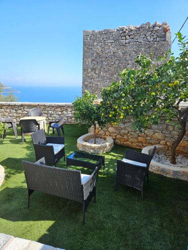 a garden with chairs and a tree and a wall at Rigas stone tower east Mani 3 in Mína