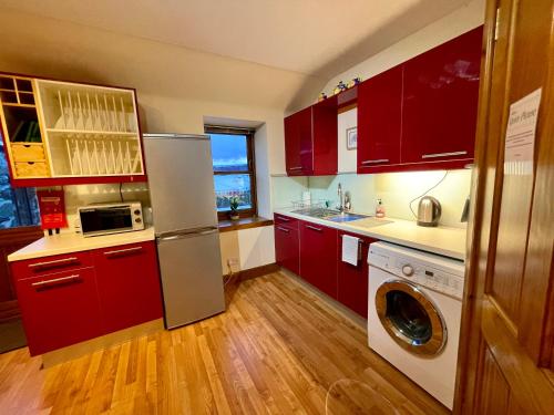 cocina con armarios rojos, lavadora y secadora en Barclay’s But n Ben, en Alford