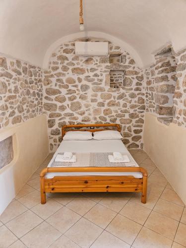 uma cama num quarto com uma parede de pedra em Rigas stone tower east Mani 3 em Mína