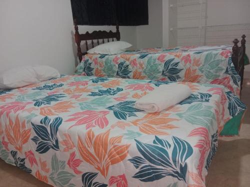 a bed with a flowered comforter with two towels on it at PARTAMENTO VALLEDUPAR in Valledupar