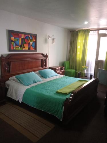 a bedroom with a large bed with a green comforter at HOTEL GALICIA PLAZA in Manizales