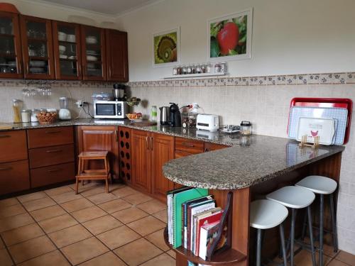 a kitchen with a counter with stools and a counter top at Casa das Palmeiras in São Vicente Ferreira