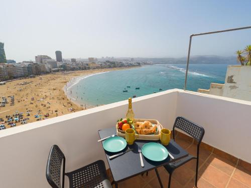- une table avec une corbeille de fruits sur un balcon avec une plage dans l'établissement Casita Canaria First Line Terrace y Seaside View, à Las Palmas de Gran Canaria
