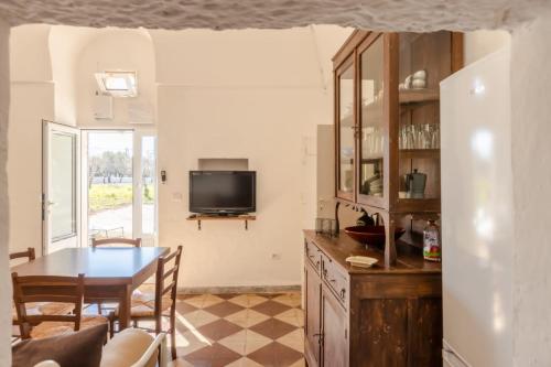 una cucina e una sala da pranzo con tavolo e TV di casina tra gli ulivi a Ostuni