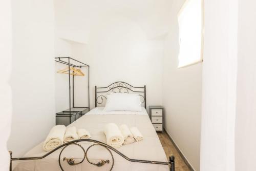 una camera bianca con un letto con lenzuola e asciugamani bianchi di casina tra gli ulivi a Ostuni