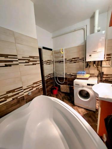 a bathroom with a tub and a washing machine at Kata Vendégház in Sátoraljaújhely
