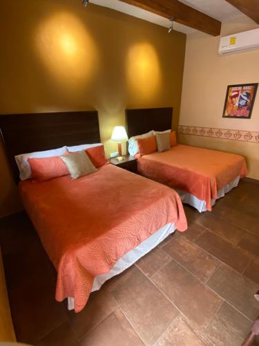 - une chambre avec 2 lits avec des draps orange dans l'établissement Hotel Casa María Félix, à Álamos
