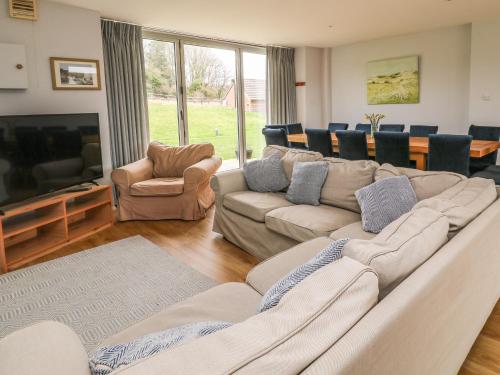 a living room with a large couch and a television at Newfield Farm Cottages in Blandford Forum