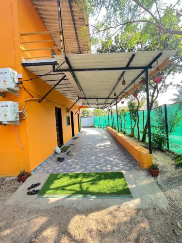 un bâtiment orange avec un tapis vert au sol dans l'établissement Shubhamkaroti Cottage, à Alībāg