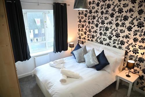 1 dormitorio con cama blanca y papel pintado en blanco y negro en Windsor to Heathrow spacious 2 Bedroom 2 Bath Apartment with Parking - Langley village Elizabeth Line to London, Reading, Oxford, en Slough