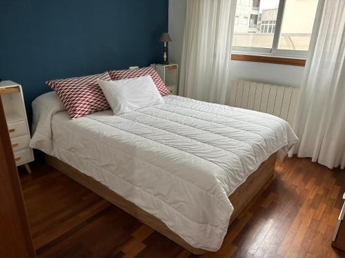 a bed with a white comforter and pillows in a bedroom at Piso Alameda Carballiño in Carballino