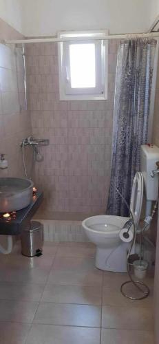 a bathroom with a toilet and a sink and a window at SOHOROS STUDIOS in Irakleia