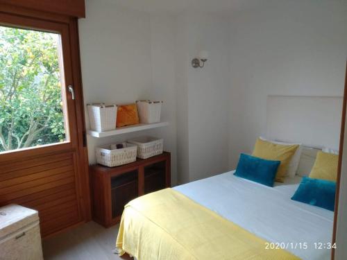 Un dormitorio con una cama con almohadas azules y una ventana en Playa de Barro, en Barro de Llanes
