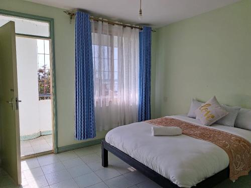 um quarto com uma cama e uma grande janela em Tamiasuites Apartment em Kisumu