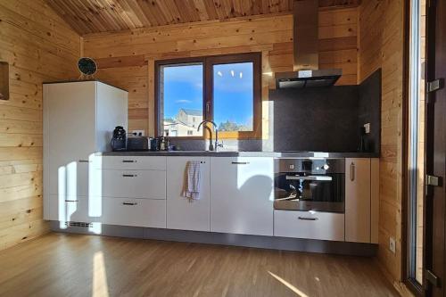 cocina con electrodomésticos blancos en una habitación con paredes de madera en Chalet Hermillon des Ardennes en Fromelennes