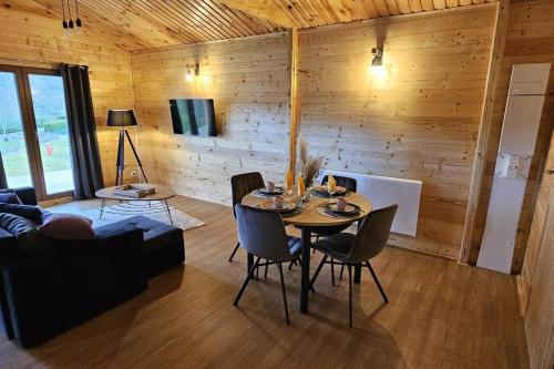 a living room with a table with chairs and a couch at Chalet Hermillon des Ardennes in Fromelennes