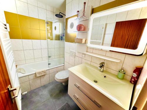 a bathroom with a sink and a toilet and a tub at Sunset View Apartment with Logia in Ettlingen