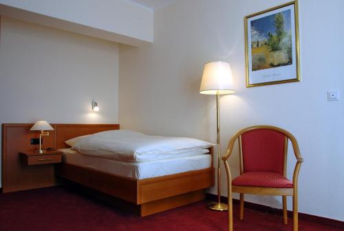 a hotel room with a bed and a chair at Altstadthotel-Rheine in Rheine