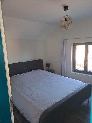 un lit dans une chambre blanche avec une fenêtre dans l'établissement Appartement 3 pièces tout confort, Aux Portes de Colmar, à Andolsheim