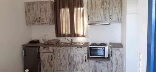 a small kitchen with wooden cabinets and a microwave at SOHOROS STUDIOS in Iraklia