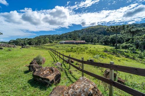 una recinzione di legno in un campo con una montagna di Pousada Morro Grande a Bom Jardim da Serra