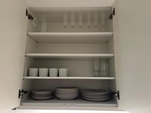 a kitchen cabinet filled with plates and bowls at Cozy apartment 2 stops-15 mins away from city center in Stockholm