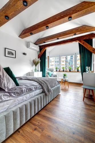 a bedroom with a large bed and wooden floors at Willa KAMELIA-apartamenty in Krynica Zdrój