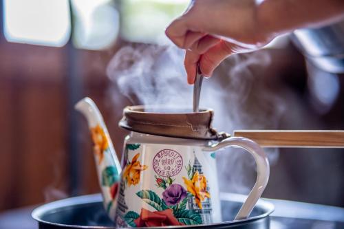 een persoon die met een lepel in een theepot roert bij Pousada Morro Grande in Bom Jardim da Serra