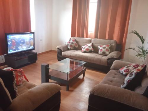 sala de estar con sofás y TV de pantalla plana. en El amanecer, en Cajamarca
