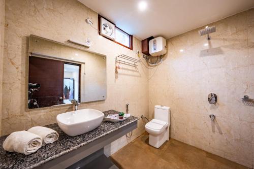 a bathroom with a sink and a toilet and a mirror at The Himalayan Stays Nainital in Nainital