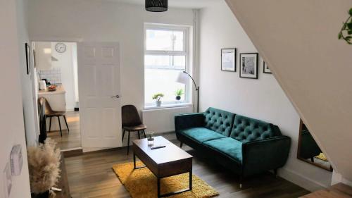 a living room with a green couch and a table at Stoke - 3 Bedroom House - Winifred St. in Stoke on Trent