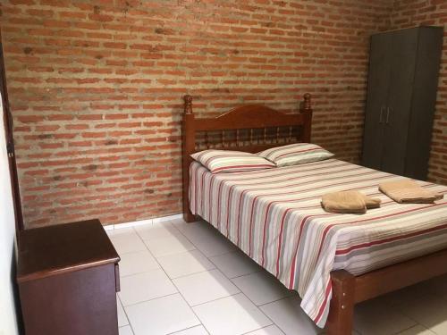 サン・ジョゼー・ダ・バーハにあるPousada Sitio Urbanoのレンガの壁、ベッド付きのベッドルーム1室