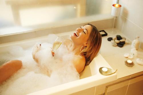 a woman laying in a bath tub with a glass of wine at Las Nalcas Boutique Hotel & Mountain Spa in El Bolsón